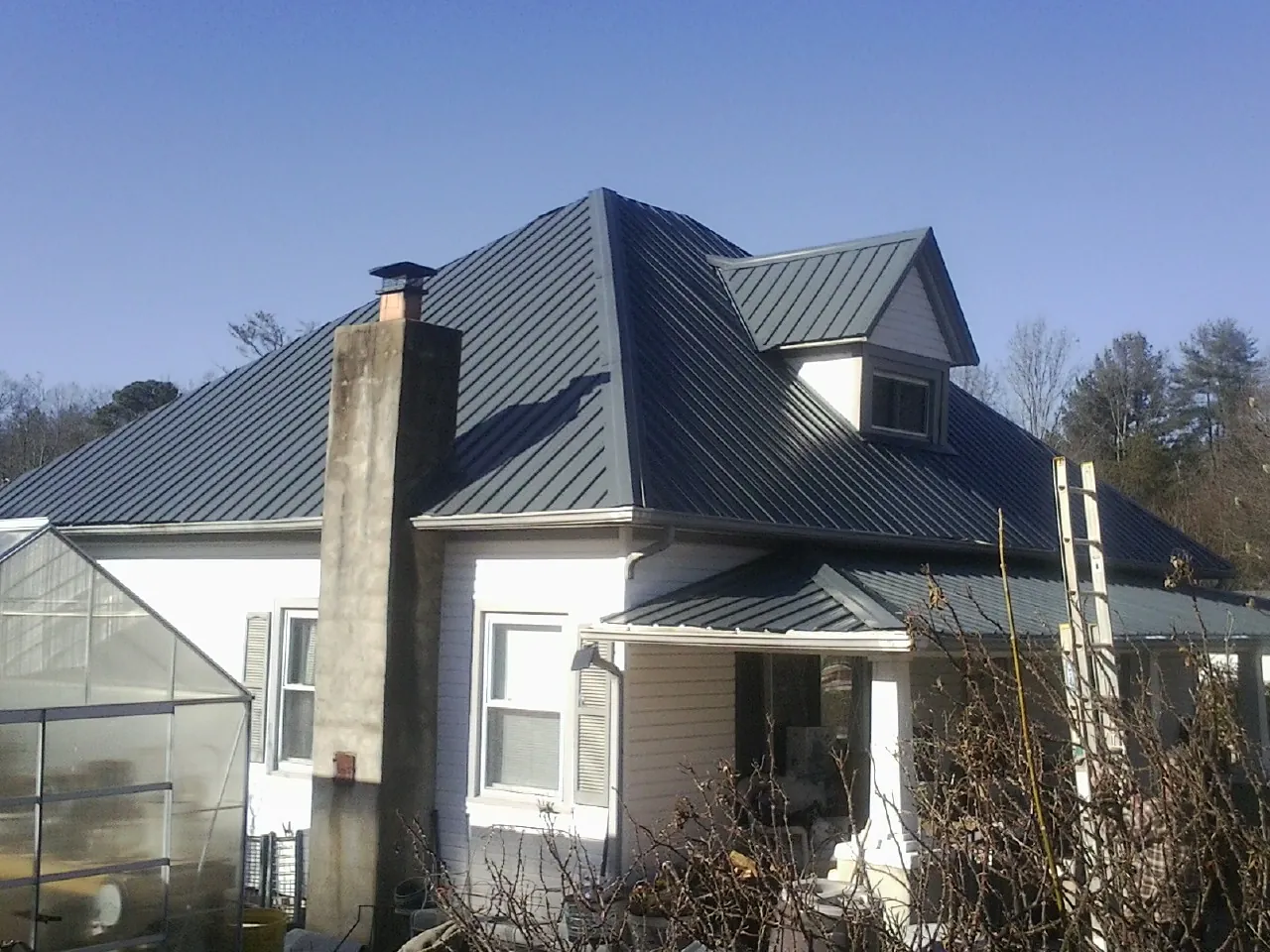 Dark blue standing seam metal roof on a white farmhouse with dormer — Slate & Tile Roof Repair by Roofing Brothers in East Lyme