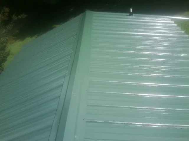 New green metal panels meeting at the ridge of a roof — Flat Roof Repair work by our crew in East Lyme