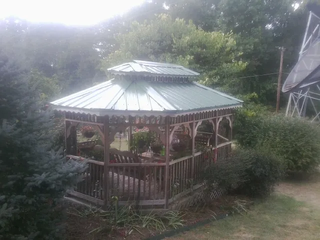 Green metal roof on a backyard gazebo surrounded by garden beds in East Lyme
