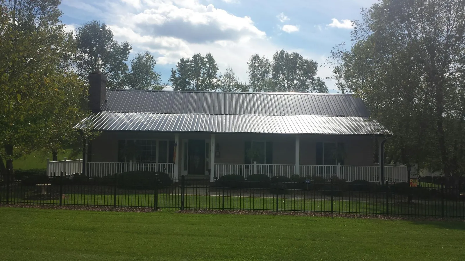 Gray metal roof on a brick ranch with a full width front porch — Gutter Guard Installation work by our crew in East Lyme