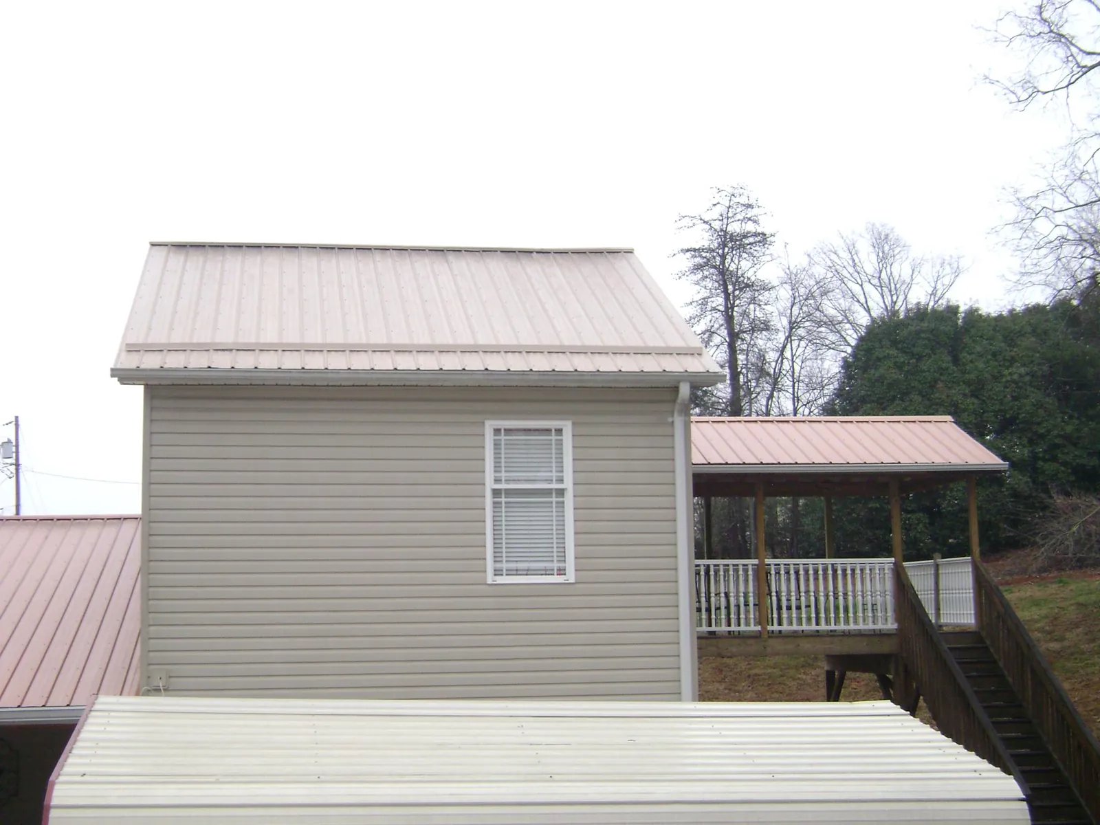 Tan metal roofs on a two story addition and attached porch, from a Roof Replacement job in East Lyme