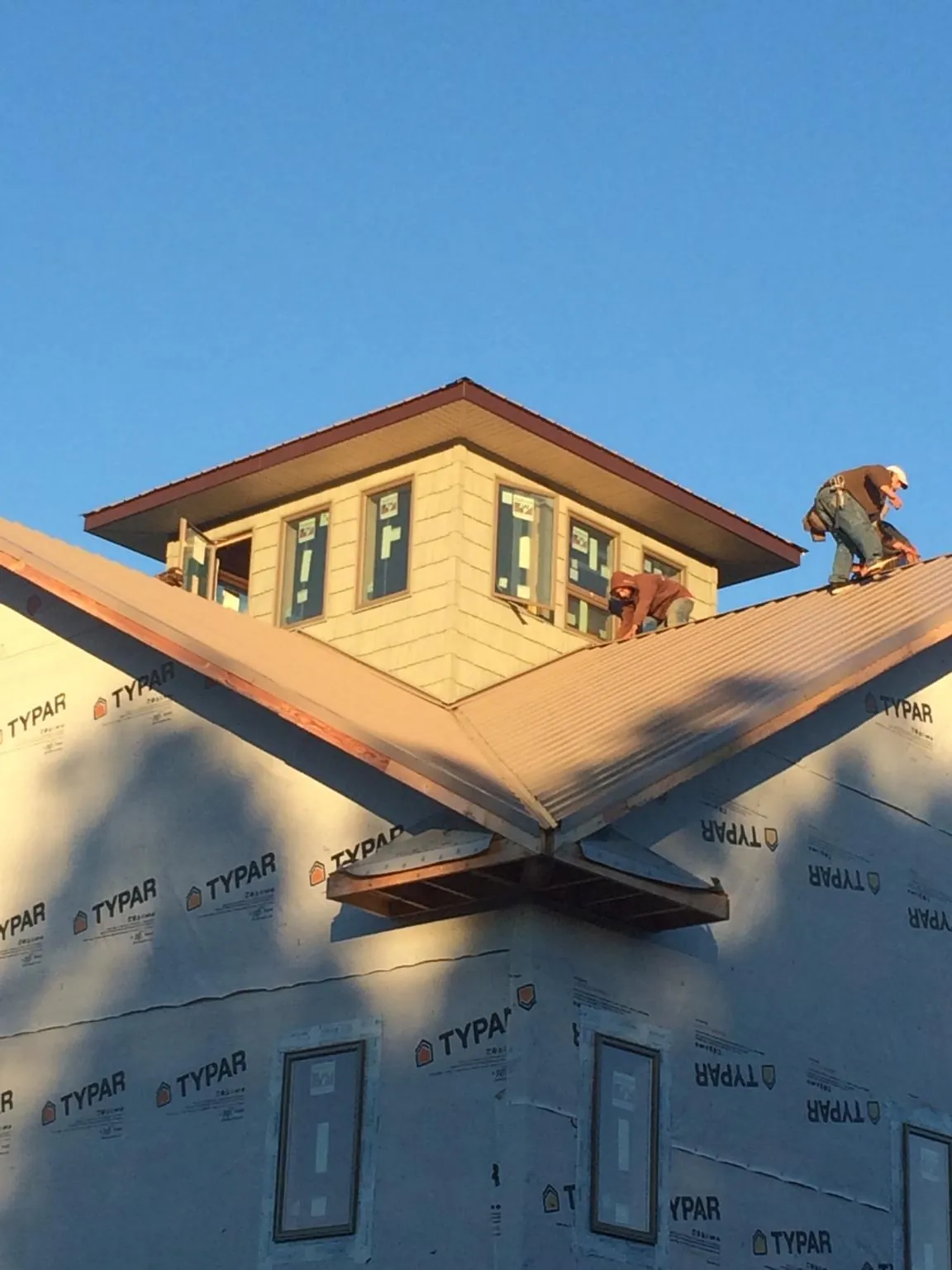 Roofers working around a rooftop cupola on a new metal roof at sunset — Roof Waterproofing in East Lyme by Roofing Brothers